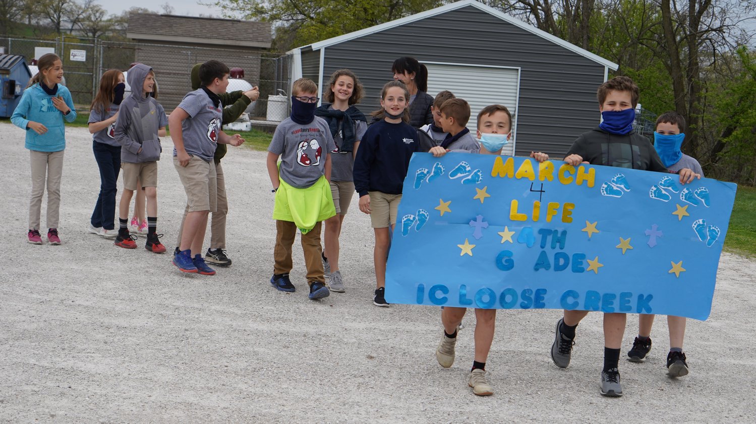 Students of Immaculate Conception School in Loose Creek carry signs and banners around the school and churchyard during a “mini march” for life on April 16.